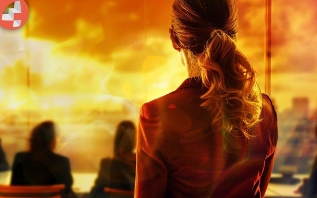 Frau mit Pferdeschwanz blickt aus Fenster in den Sonnenuntergang