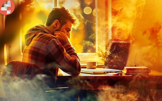 Mann im karierten Hemd konzentriert am Laptop.