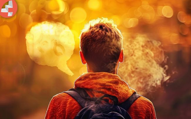 Person mit Rucksack, die in einem herbstlichen Park steht.